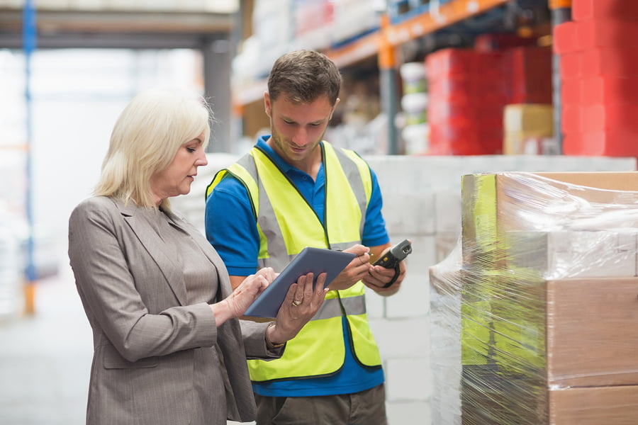 Manager using BPM solution on tablet while worker scanning package in warehouse Manager using BPM solution on tablet while worker scanning package in warehouse